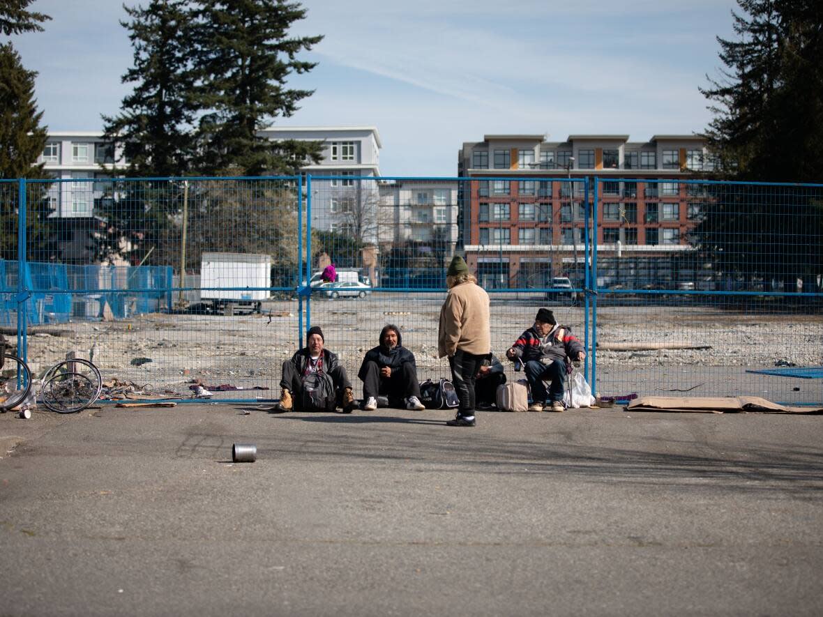 Men sit on the street outside the Surrey Urban Mission Society in Surrey in March  2020. A new project driven by Surrey teenagers aims to help unhoused people in the city. (Maggie MacPherson/CBC - image credit)