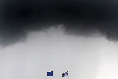 A Greek national flag and a European Union flag flutter under storm clouds in Athens, Greece in this May 28, 2015 file photo. REUTERS/Alkis Konstantinidis/Files