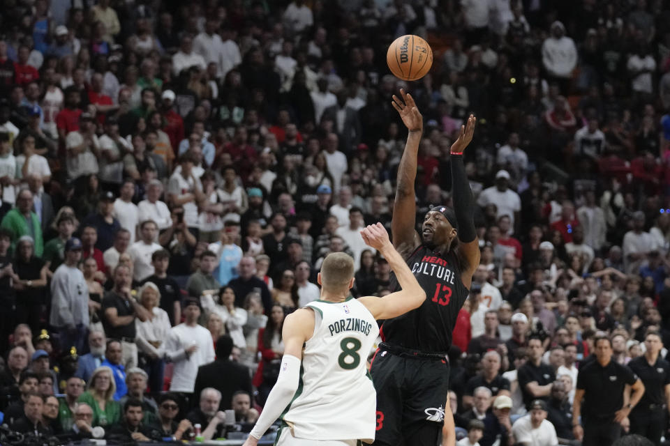 Miami Heat center Bam Adebayo (13) shoots a basket past Boston Celtics center Kristaps Porzingis (8) during the second half of an NBA basketball game, Sunday, Feb. 11, 2024, in Miami. (AP Photo/Rebecca Blackwell)