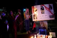 <p>Demonstrators burn a hijab in protest at a candlelit vigil following the death of a young Iranian Kurdish woman, Zhina Mahsa Amini, outside the Wilshire Federal Building in Los Angeles, California, U.S., September 22, 2022. REUTERS/Bing Guan</p> 