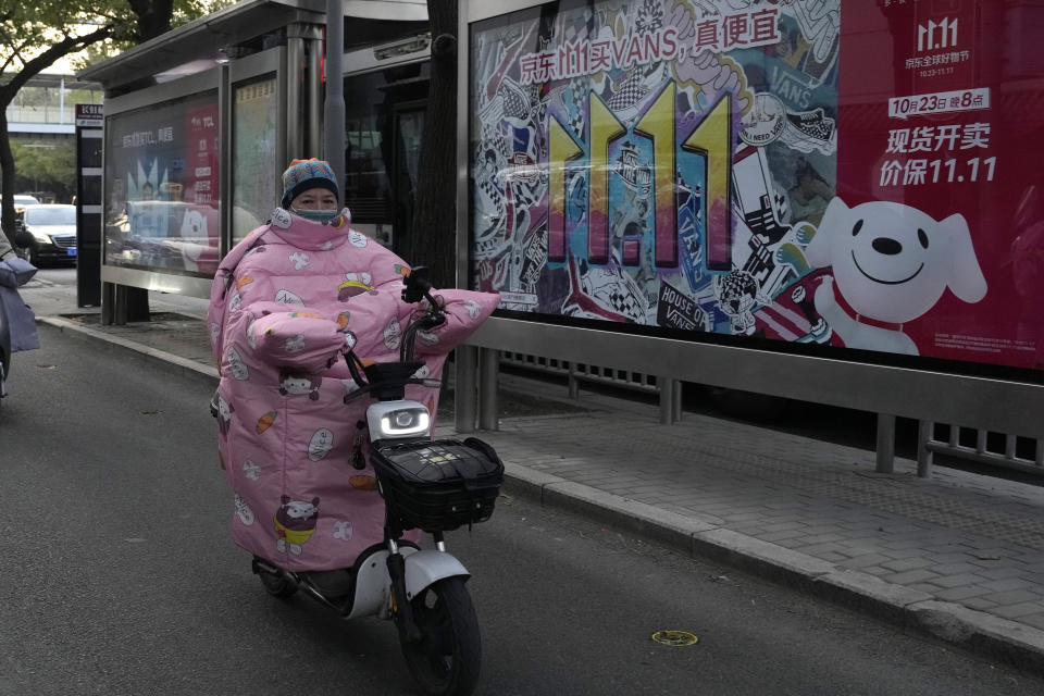 A resident rides past an advertisement for Singles' Day in Beijing, Wednesday, Nov. 8, 2023. Shoppers in China have been tightening their purse strings, raising questions over how faltering consumer confidence may affect the annual Singles' Day online retail extravaganza. (AP Photo/Ng Han Guan)