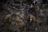 Ukrainian soldiers help a man on a wheelchair as people try to flee crossing the Irpin river in the outskirts of Kyiv, Ukraine, Saturday, March 5, 2022. (AP Photo/Emilio Morenatti)