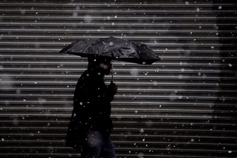 A person walks with an umbrella in the snow in the Manhattan borough of New York City