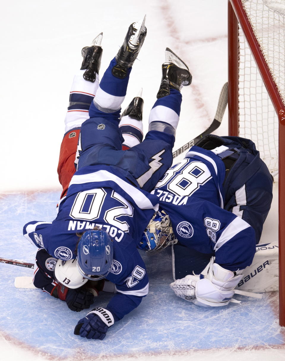 Tampa Bay Lightning center Blake Coleman (20) drives Columbus Blue Jackets right wing Cam Atkinson (13) into the ice over Lightning goaltender Andrei Vasilevskiy (88) during the first period in Game 1 of an NHL hockey Stanley Cup first-round playoff series, Tuesday, Aug. 11, 2020, in Toronto. (Frank Gunn/The Canadian Press via AP)