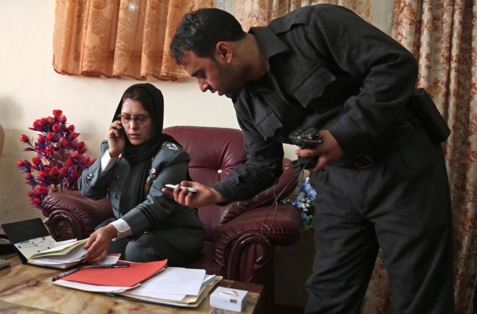 Afghanistan's first-ever female district police chief, Col. Jamila Bayaz, 50, left, talks on the phone at her office in Kabul, Afghanistan, Thursday, Jan. 16, 2014. Afghanistan's first-ever female district police chief drew stares on Thursday as she drove and walked around the center of the city, reviewing check points and some of the important business and administrative facilities she is tasked with protecting. (AP Photo/Massoud Hossaini)