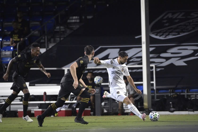 The Galaxy's Sebastian Lletget kicks the ball as LAFC's Mark-Anthony Kaye, far left, and Dejan Jakovic defend July 18.