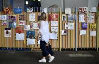 A woman looks at paintings and drawings left for the victims of the fire at the Grenfell apartment tower in North Kensington, London, Britain, June 23, 2017. REUTERS/Hannah McKay