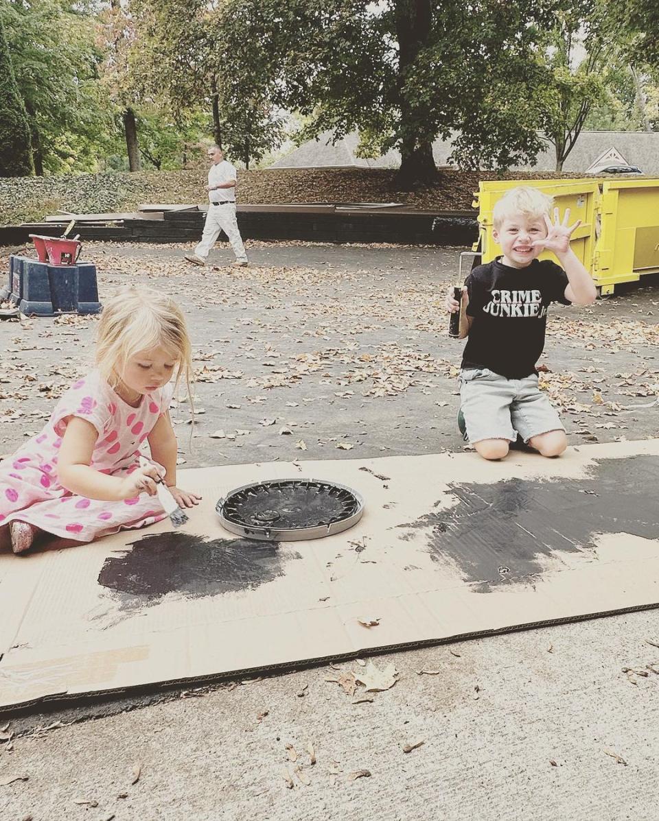 Jack and Charlotte Hawk paint on a cardboard box