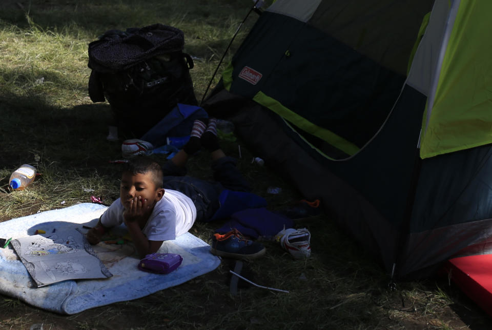 A boy lies with a coloring book outside a tent inside the sports complex where thousands of migrants have been camped out for several days in Mexico City, Friday, Nov. 9, 2018. About 500 Central American migrants headed out of Mexico City on Friday to embark on the longest and most dangerous leg of their journey to the U.S. border, while thousands more were waiting one day more at a massive improvised shelter.(AP Photo/Rebecca Blackwell)