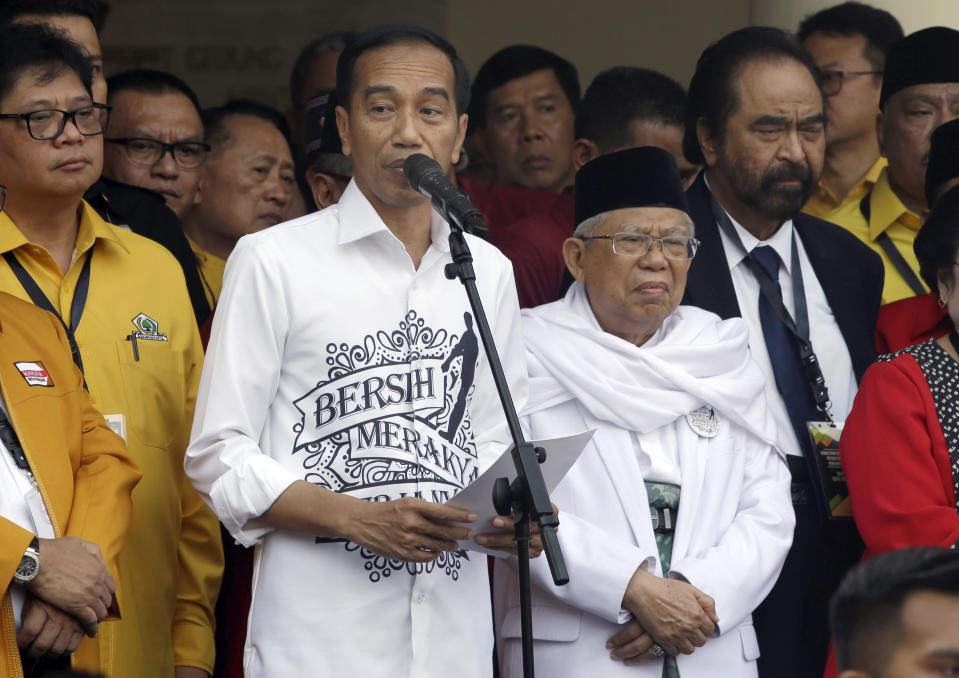 Indonesian President Joko "Jokowi" Widodo, center left, speaks as his running mate Ma'ruf Amin, center right, listens prior to formal registration as candidates for the 2019 presidential election in Jakarta, Indonesia. Friday, Aug. 10,2018. The battle lines for Indonesia's 2019 presidential election were drawn Friday as president Jokowi formally registered as a candidate after choosing a conservative Islamic cleric as his running mate. (AP Photo/Tatan Syuflana)