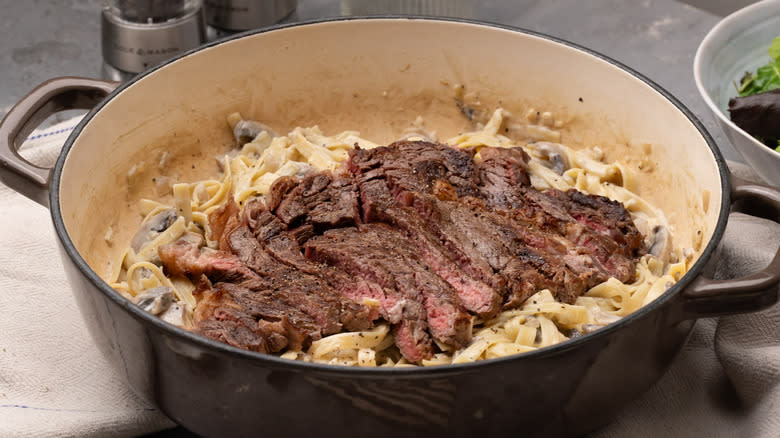 mushroom fettuccine pasta with steak in pan