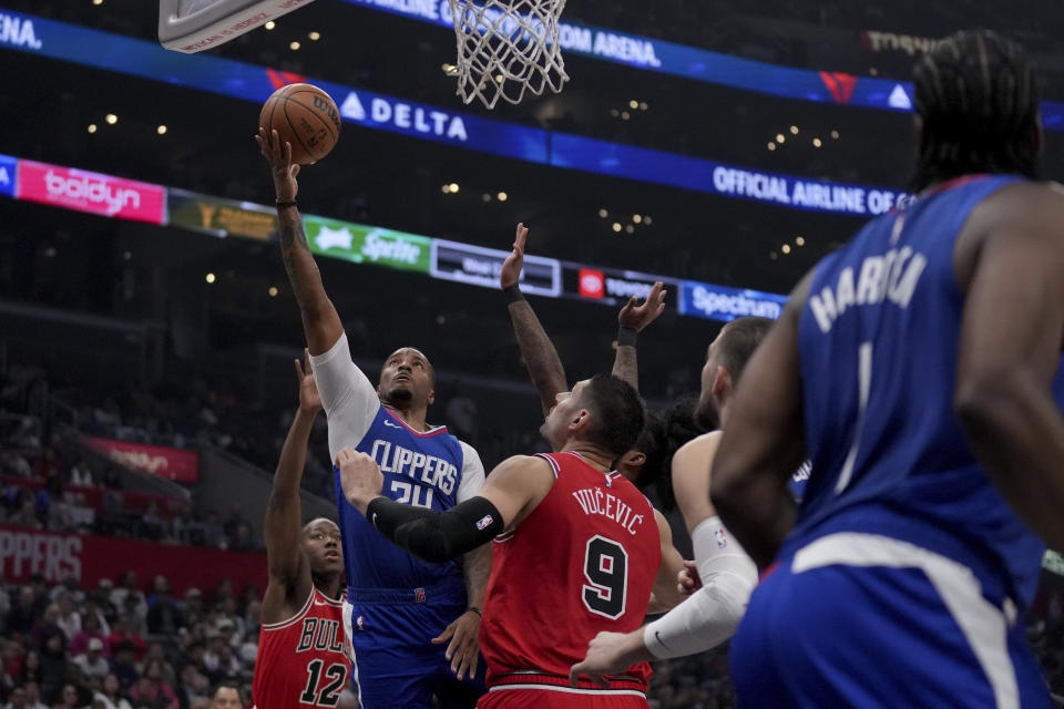 Los Angeles Clippers guard Norman Powell (24) goes to the basket against Chicago Bulls guard Ayo Dosunmu (12) and center Nikola Vucevic (9) during the first half of an NBA basketball game in Los Angeles, Saturday, March 9, 2024. (AP Photo/Eric Thayer)