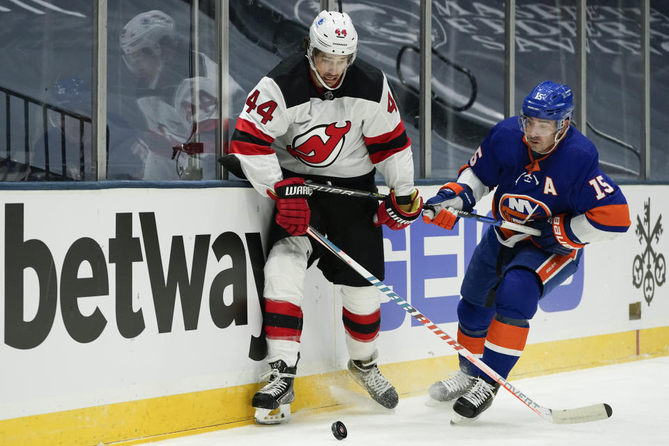 New Jersey Devils' Miles Wood (44) fights for control of the puck with New York Islanders' Cal Clutterbuck (15) during the first period of an NHL hockey game Thursday, Jan. 21, 2021, in Uniondale, N.Y. (AP Photo/Frank Franklin II)