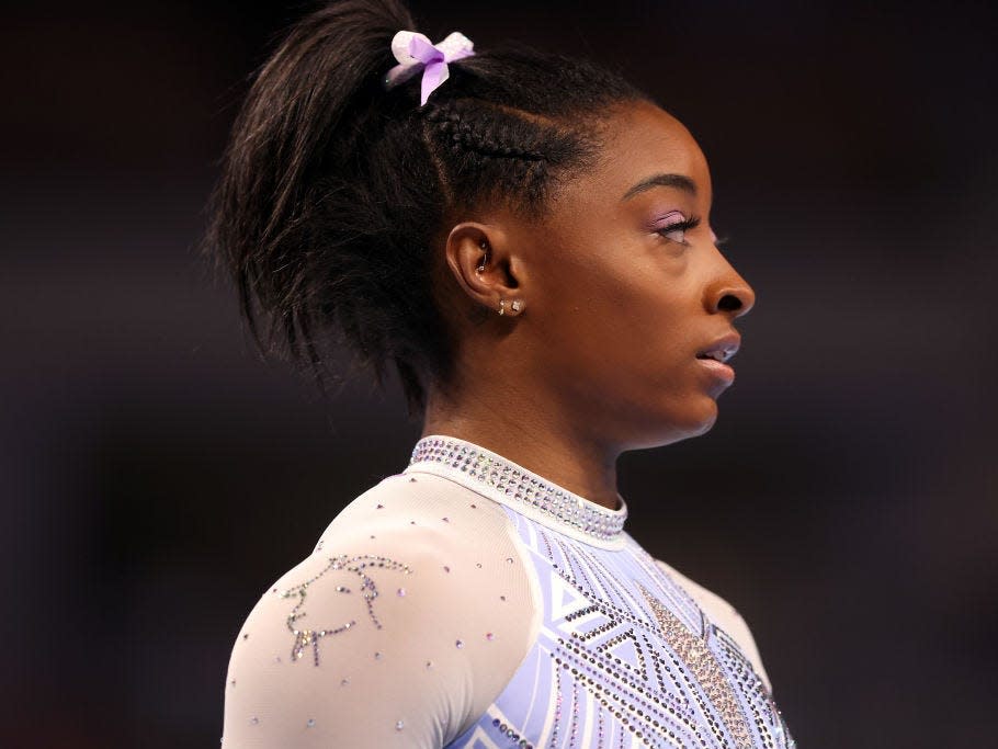 Simone Biles wearing a leotard with a rhinestone goat on the shoulder.