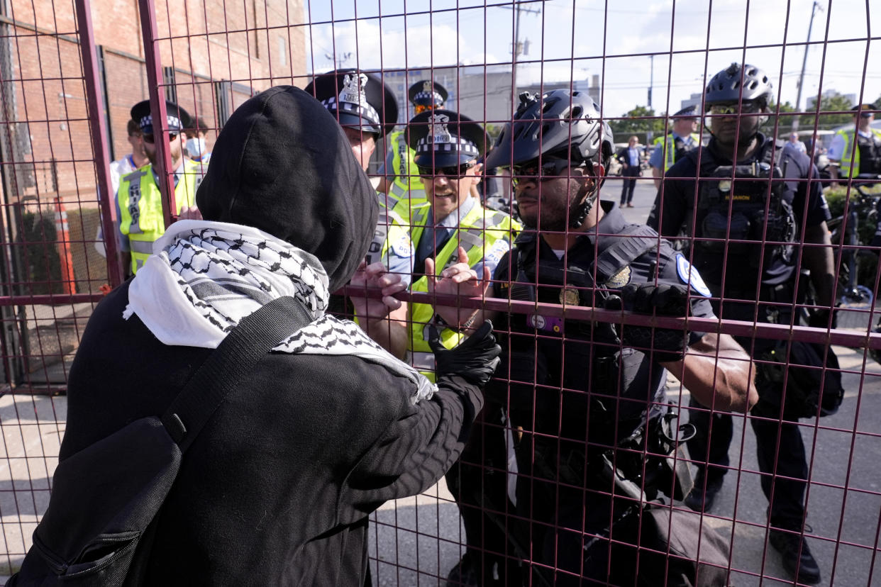 A protester tries to push through a fence surrounding the United Center during the Democratic National Convention in Chicago Monday.