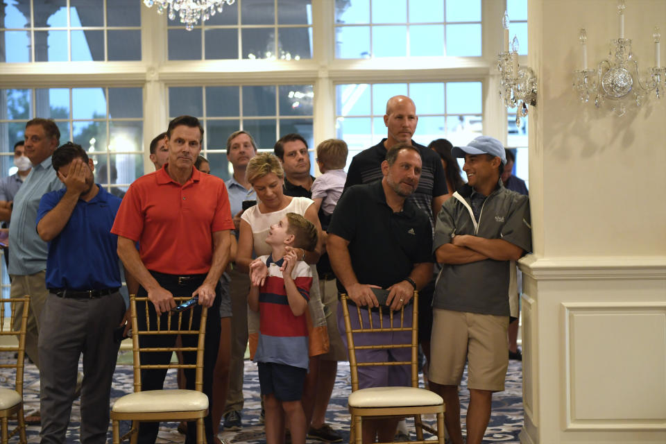 People stand behind chairs as they wait to watch President Donald Trump speak at Trump National Golf Club Bedminster in Bedminster, N.J., Friday, Aug. 7, 2020. (AP Photo/Susan Walsh)