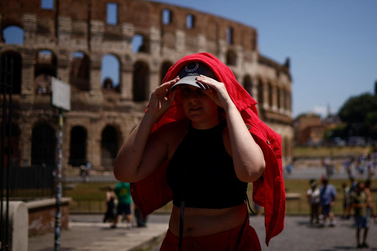 A woman shelters from the sun with a shirt near the Colosseum (REUTERS)