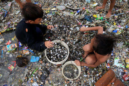 Children take advantage of the gloomy weather to collect washed up clams brought by crashing waves due to strong winds of Super Typhoon Haima, local name Lawin, along the coastal areas in metro Manila, Philippines October 20, 2016. REUTERS/Romeo Ranoco