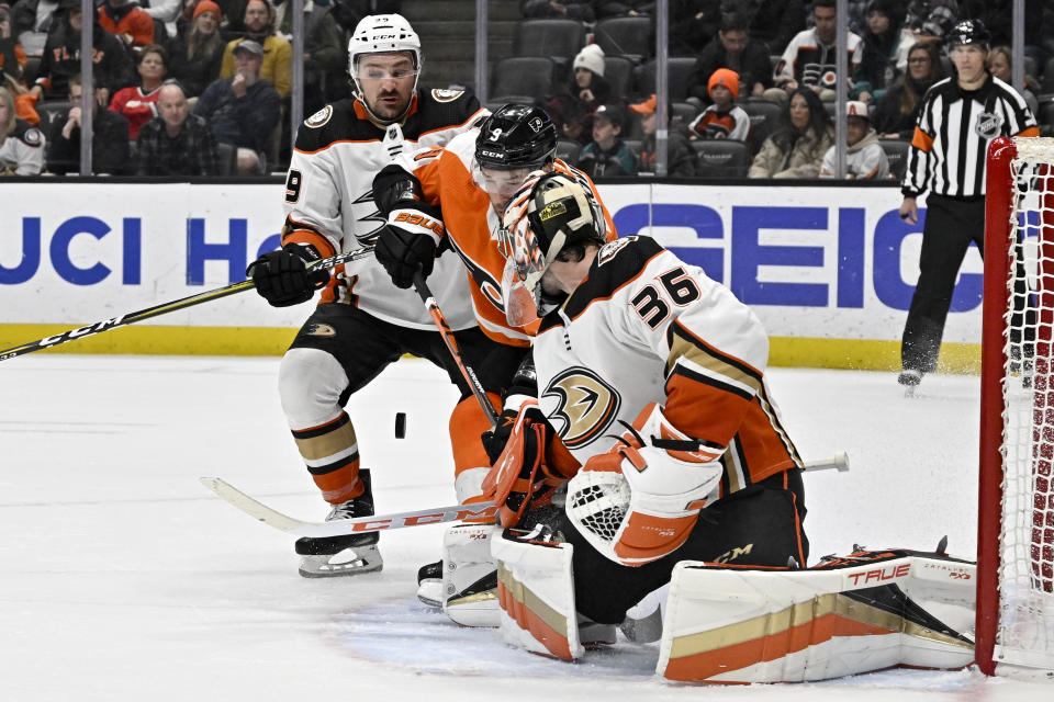 Anaheim Ducks goaltender John Gibson, right, redirects the puck with Philadelphia Flyers defenseman Ivan Provorov, center, attacking and Ducks center Sam Carrick defending during the first period of an NHL hockey game in Anaheim, Calif., Monday, Jan. 2, 2023. (AP Photo/Alex Gallardo)