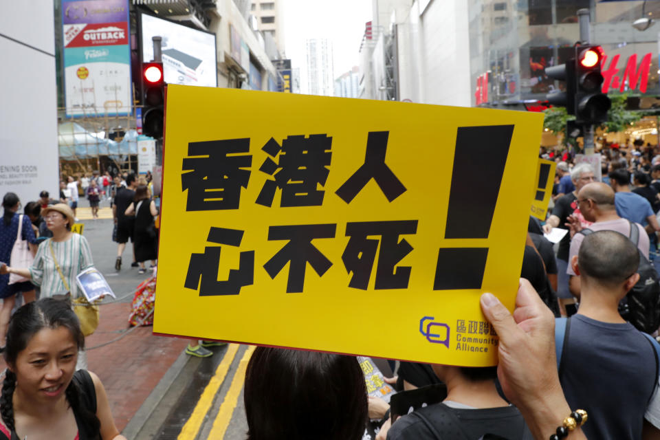 A protester holds up a sign that reads: "Hong Kongers won't give up!" in Hong Kong Sunday, Aug. 18, 2019. A spokesman for China's ceremonial legislature condemned statements from U.S. lawmakers supportive of Hong Kong's pro-democracy movement, as more protests were planned Sunday following a day of dueling rallies that highlighted the political divide in the Chinese territory. (AP Photo/Vincent Thian)