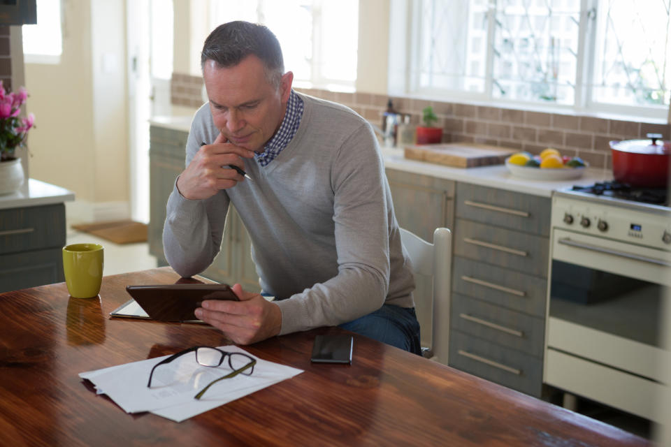 Older man in kitchen looking at tablet