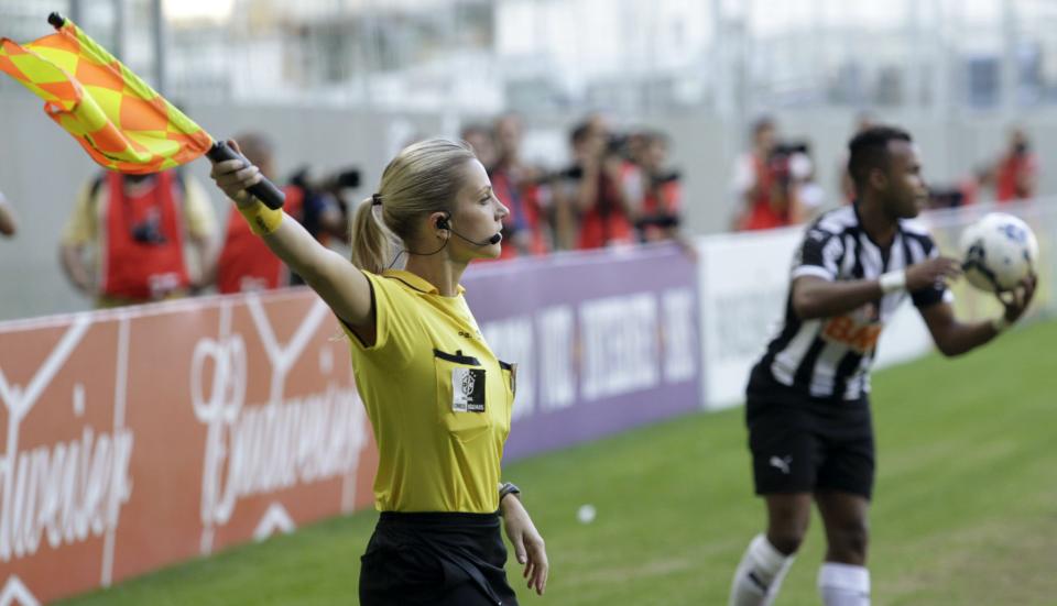 Brazil's referee assistant Fernanda Colombo Uliana signs her flag next to Atletico Mineiro's Fernandinho during the Brazilian championship soccer match between Atletico Mineiro and Cruzeiro in Belo Horizonte