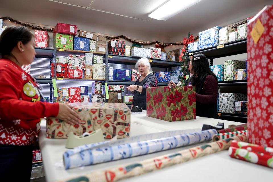 Joy Kosta points to a box as Heidi Campbell and Francia Luedtke-Bautista wrap presents this month for patients at Oregon State Hospital in Salem and Junction City.