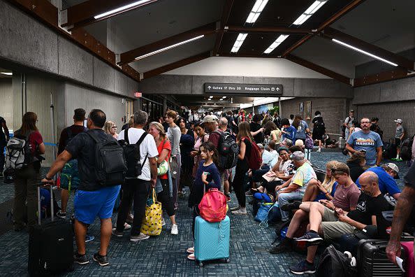 Passengers try to rest and sleep after canceled and delayed flights while others wait to board flights off the island as thousands of passengers were stranded at the Kahului Airport (OGG) in the aftermath of wildfires in western Maui in Kahului, Hawaii on August 9, 2023. The death toll from a wildfire that turned a historic Hawaiian town to ashes has risen to 36 people, officials said on August 9. (Photo by Patrick T. Fallon / AFP) (Photo by PATRICK T. FALLON/AFP via Getty Images)