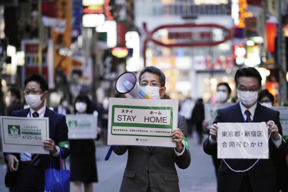 FILE - In this April 24, 2020, file photo, staff of the Tokyo Metropolitan Government urge people to go home from the Kabukicho entertainment district in the Shinjuku Ward in Tokyo. Under Japan's coronavirus state of emergency, people have been asked to stay home. Many are not. Some still have to commute to their jobs despite risks of infection, while others are dining out, picnicking in parks and crowding into grocery stores with scant regard for social distancing. (AP Photo/Eugene Hoshiko, File)