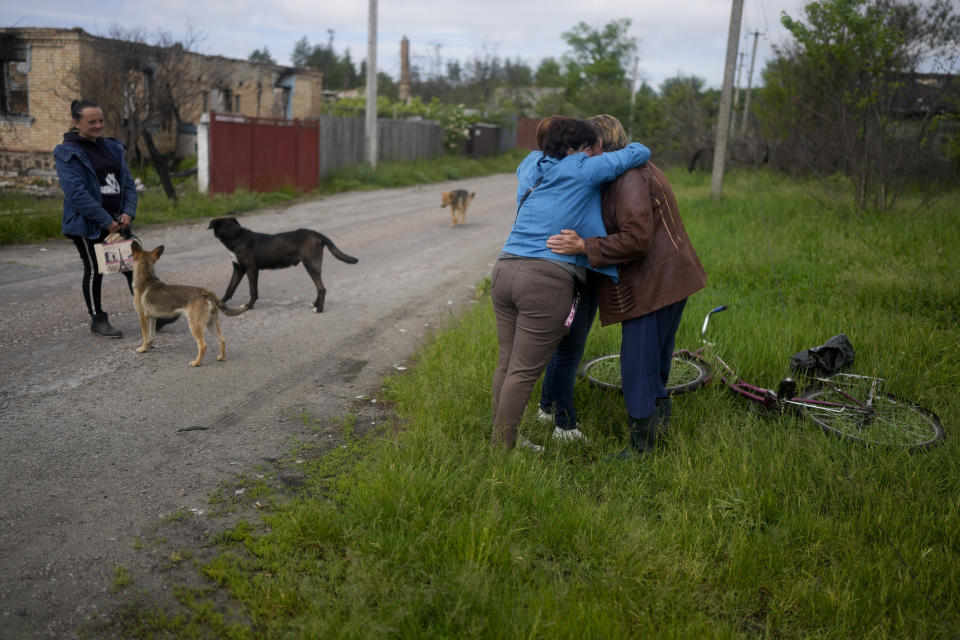 Nila Zelinska, center, and Natalia Didenko, left, embrace a neighbor as they both arrive to their home town after escaping war in Potashnya, on the outskirtsof Kyiv, Ukraine, Tuesday, May 31, 2022. (AP Photo/Natacha Pisarenko)