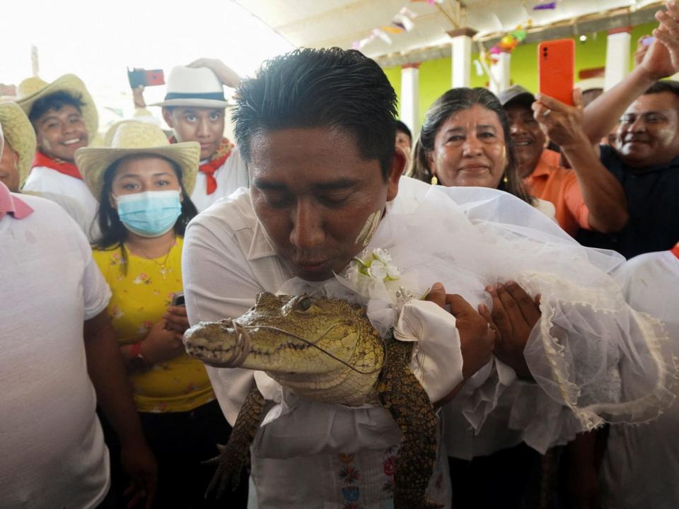 The San Pedro Huamelula Mayor Victor Hugo Sosa kisses a seven-year-old alligator dressed as a bride during a traditional ritual marriage, likely dates back centuries to pre-Hispanic times, between the mayor and the reptile that depicts a princess, as a prayer to plead for nature's bounty, in San Pedro Huamelula, in Oaxaca state, Mexico June 30, 2022. REUTERS/Jose de Jesus Cortes