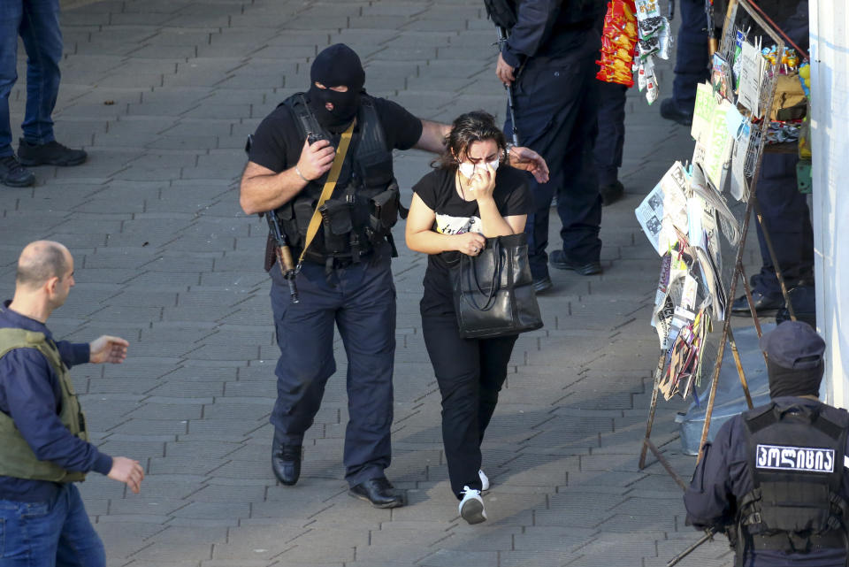 Georgian police officers escorts a woman who escaped from a bank where an armed assailant has taken several people hostage, in the town of Zugdidi in western Georgia, Wednesday, Oct. 21, 2020. The Georgian Interior Ministry didn't immediately say how many people have been taken hostage in the town of Zugdidi in western Georgia, or what demands the assailant has made. Police sealed off the area and launched an operation "to neutralize the assailant," the ministry said in a statement. (AP Photo/Zurab Tsertsvadze)