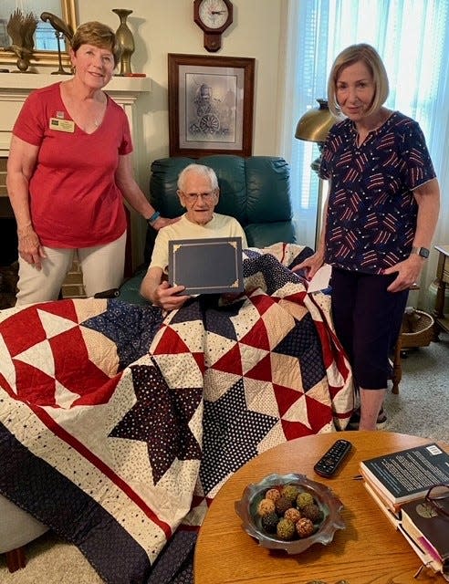 World War II veteran William Douglas Brown receives a quilt from quilters Didi Salvatierra, left, and Sheila Solen.