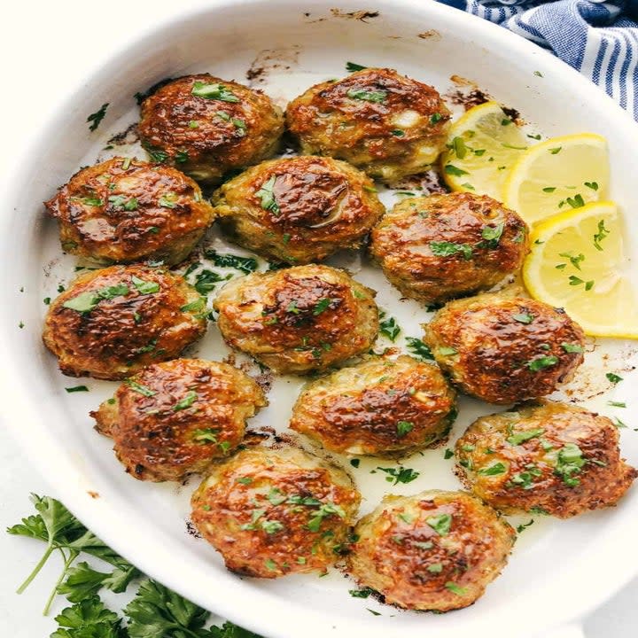 Meatballs on a serving platter with herbs.