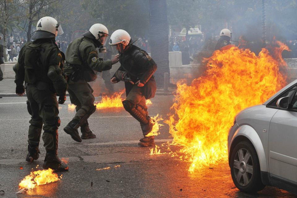 ATHENS, GREECE - DECEMBER 15: Police run from a fire bomb during clashs with austerity protesters December 15, 2010 in Athens, Greece. Violence erupted after approximately 20, 000 protestors marched to parliament during a 24-hour general strike over labor reforms. Protestors reportedly clashed with riot police throughout Athens, buring cars and throwing gasoline bombs (Photo by Milos Bicanski/Getty Images)