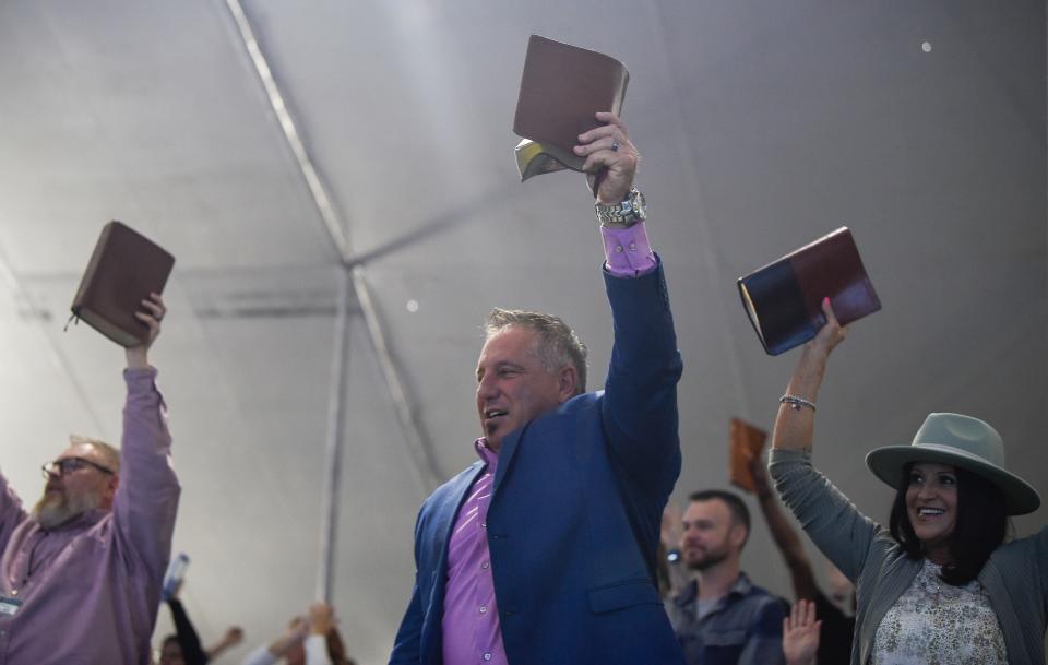 Greg and Lisa Birches raise their bibles up in the air as Pastor Greg Locke does his sermons at the Global Vision Bible Church in Mt. Juliet, Tenn., Sunday, April 3, 2022.