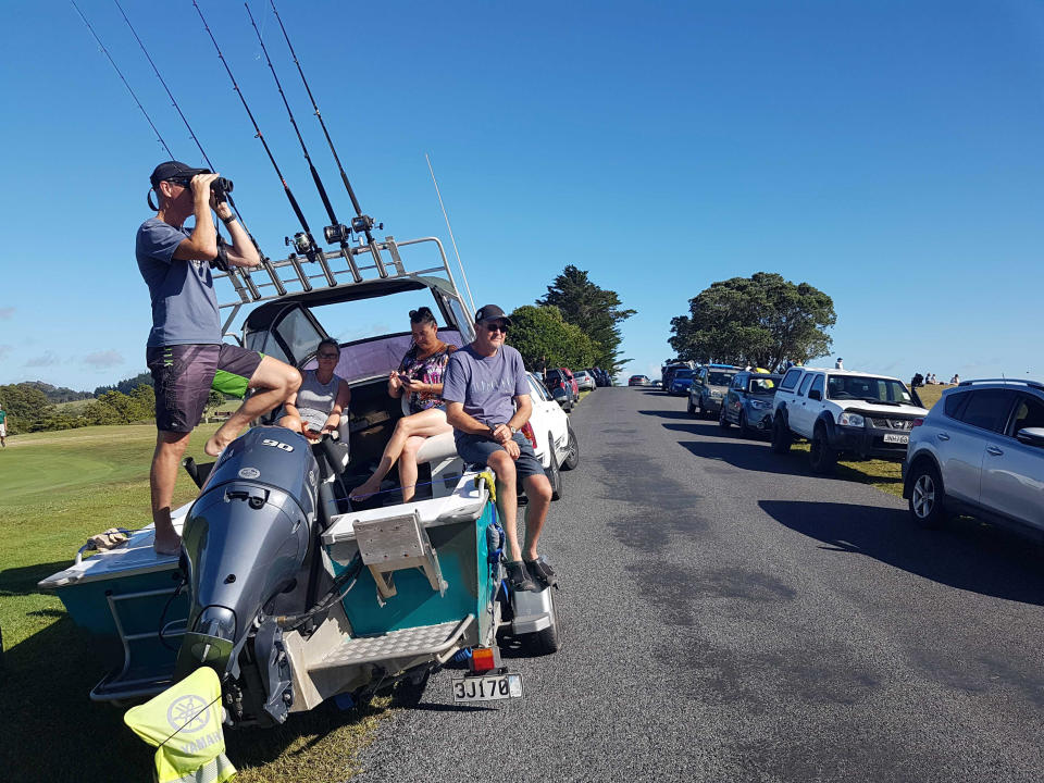 John Fitzgerald, left, on holidays with his wife Rita and friends, scans the horizon from high ground for any sign of a tsunami near Waitangi, New Zealand, Friday, March 5, 2021. A powerful magnitude 8.1 earthquake struck in the ocean off the coast of New Zealand prompting thousands of people to evacuate and triggering tsunami warnings across the South Pacific. (Peter De Graaf/New Zealand Herald via AP)