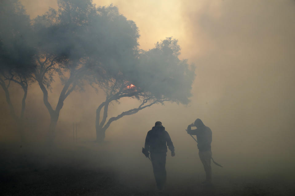 Dean Cato, left, and his son Robert use shovels to try to put out hotspots caused by the Easy fire at American Soil and Nursery Wednesday, Oct. 30, 2019, in Simi Valley, Calif. A new wildfire erupted Wednesday in wind-whipped Southern California, forcing the evacuation of the Ronald Reagan Presidential Library and nearby homes, as both ends of the state struggled with blazes, dangerously gusty weather and deliberate blackouts. (AP Photo/Marcio Jose Sanchez)