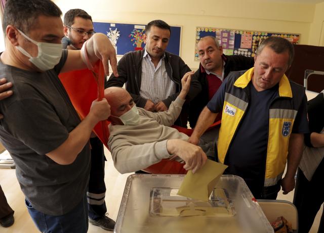 Cevat Cinar on a stretcher casts his ballot at a polling station in Ankara, Turkey, Sunday, May 14, 2023. Turkey is voting in pivotal parliamentary and presidential elections that are expected to be tightly contested and could be the biggest challenge President Recep Tayyip Erdogan has faced in his two decades in power. (AP Photo)