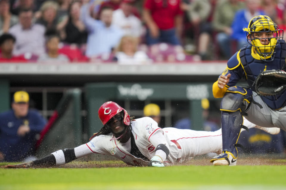 Cincinnati Reds' Elly De La Cruz, left, scores a run ahead of a play by Milwaukee Brewers' William Contreras, right, during the fourth inning of a baseball game in Cincinnati, Monday, April 8, 2024. (AP Photo/Aaron Doster)