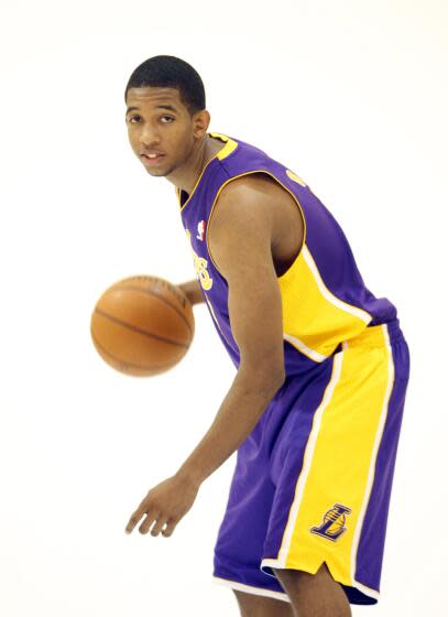 Darius Morris is holding a basketball and wearing his Lakers uniform