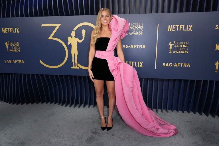 Margot Robbie sigue con su estilo Barbie para las alfombras rojas de la temporada de premiación 2024. La actriz y productora de uno de los films más nominados lució un vestido negro corto que destacó con un aplique que desde el escote hasta la cola, color rosa. El look llevó la firma de Schiaparelli
