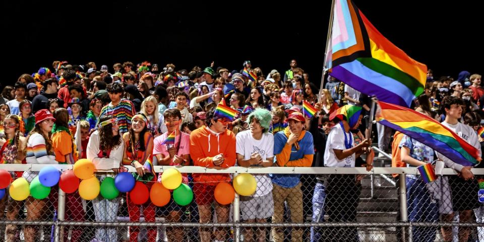 The crowd at Burlington High School's homecoming game cheers on performers while decked out in rainbow colors.