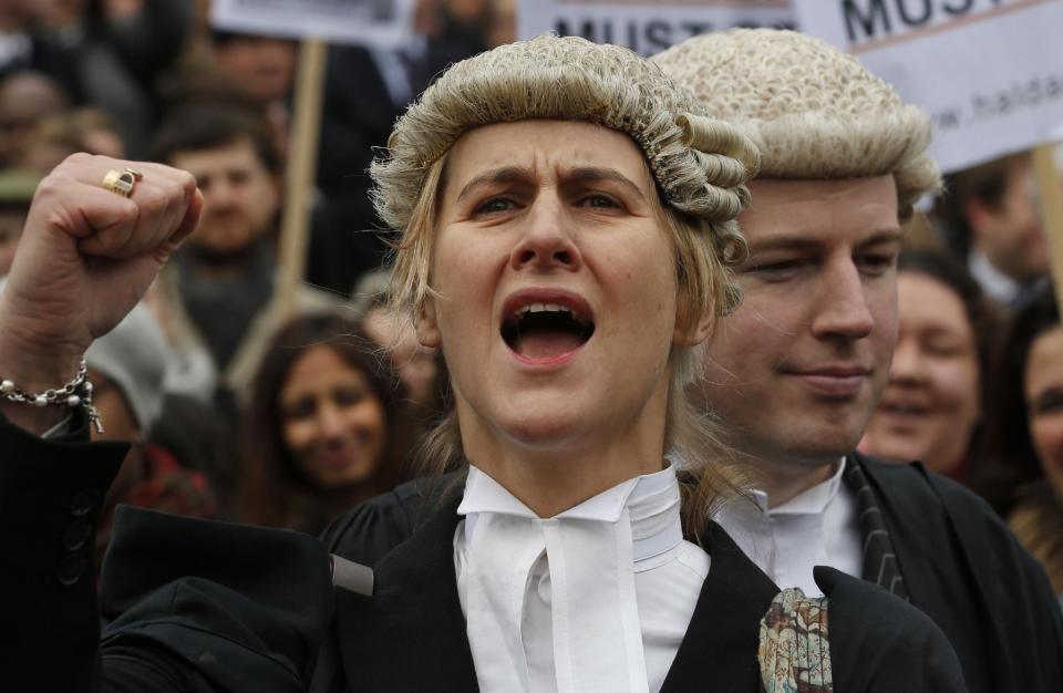 Barrister Juliet Donovan in her full court dress of wig and gown, chants slogans during a rally to protest against legal aid cuts, across from the Houses of Parliament in central London, Friday, March 7, 2014. The protest coincides with a nationwide demonstration of non-attendance of lawyers which will affect hundreds of cases across the country. (AP Photo/Lefteris Pitarakis)