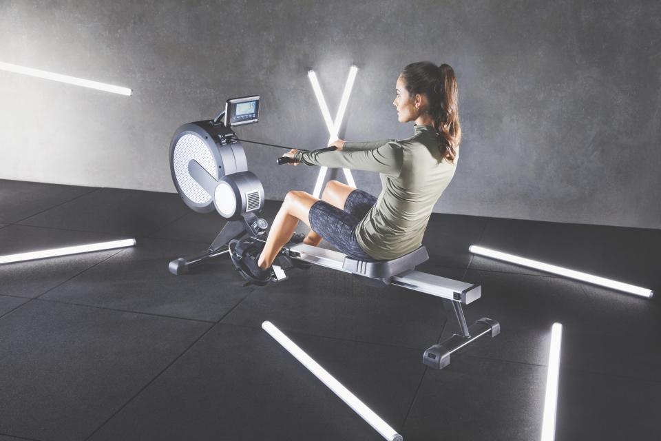 A woman wearing exercise clothing uses an Air resistance rower