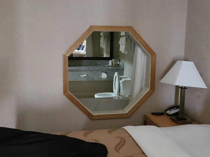 Hotel room with a window into the bathroom where you can see the toilet from the bed