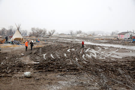 Protesters walk through deep mud in the main opposition camp against the Dakota Access oil pipeline near Cannon Ball, North Dakota, U.S., February 22, 2017. REUTERS/Terray Sylvester