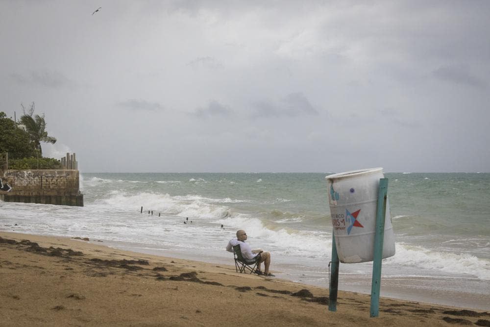 A man sits in front of a beach watching as the waves break before the arrival of Tropical Storm Fiona in San Juan, Puerto Rico, Saturday, Sept. 17, 2022. Fiona was expected to become a hurricane as it neared Puerto Rico on Saturday, threatening to dump up to 20 inches (51 centimeters) of rain as people braced for potential landslides, severe flooding and power outages. (AP Photo/Alejandro Granadillo)