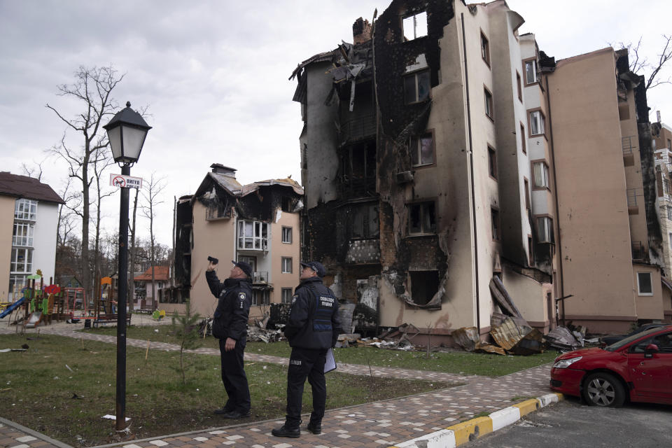 Police officers take pictures of buildings damaged by shelling in Irpin, in the outskirts of Kyiv, Ukraine, Monday, April 11, 2022. (AP Photo/Evgeniy Maloletka)