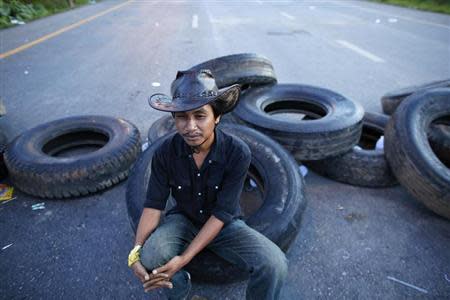 A rubber farmer rests on a tyre at a road block where he and others spent the night during a protest in Surat Thani, early September 4, 2013. REUTERS/Athit Perawongmetha